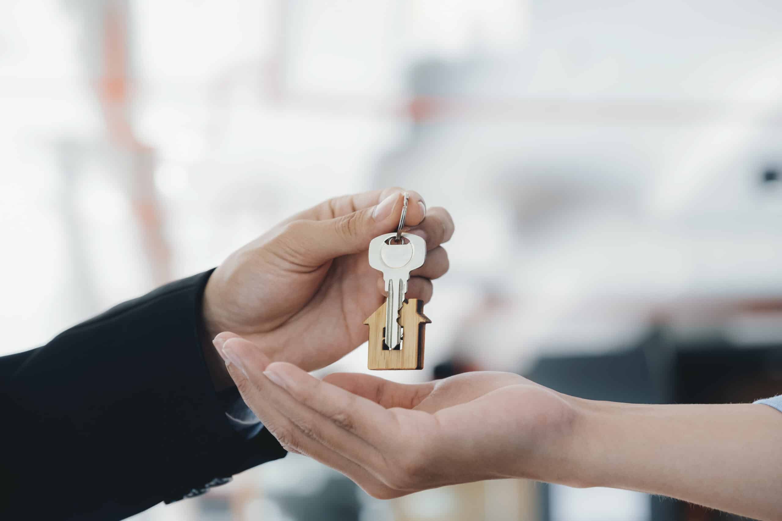 real estate agent holding key with house shaped keychain.